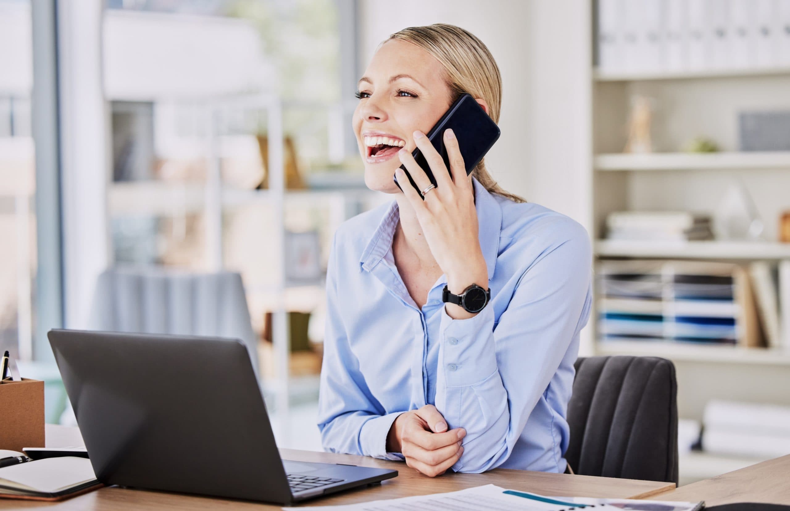 Geschäftsfrau telefoniert motiviert am Büroschreibtisch