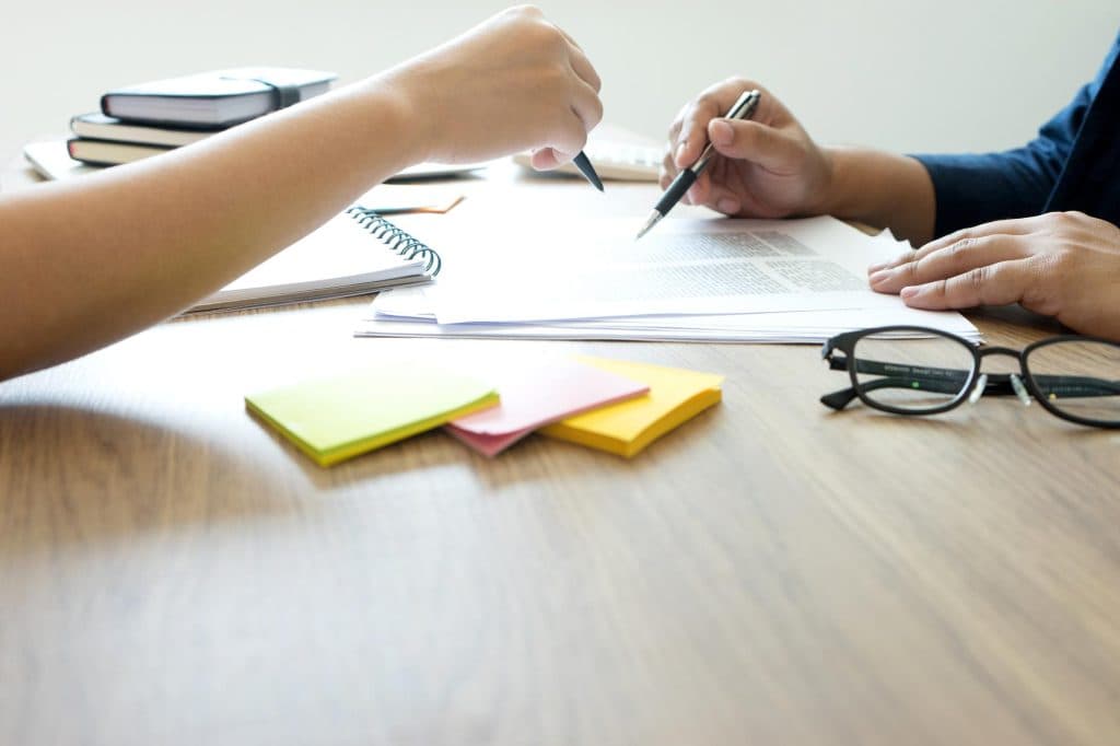Vertrag im Handel auf Tisch, Brille und Hände mit Schreiber