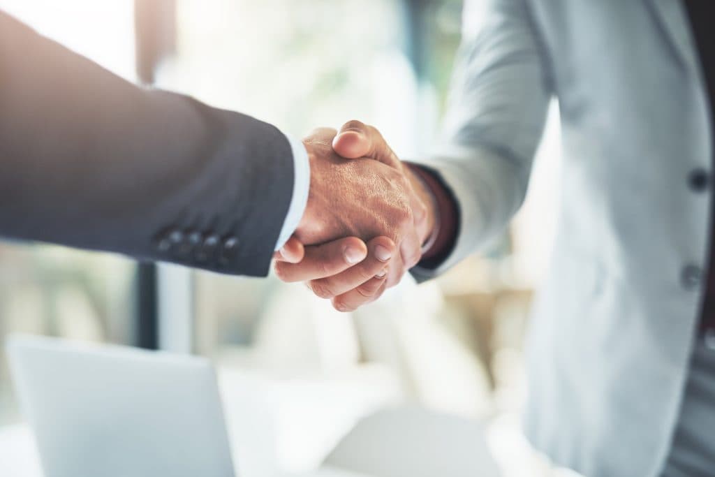 Händeschütteln im Büro als Symbol für eine partnerschaftliche B2B-Zusammenarbeit